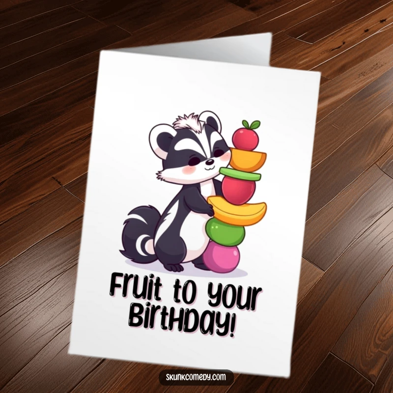 Funny free printable birthday card of a skunk precariously balancing a tower of colorful fruits, ready to tumble.